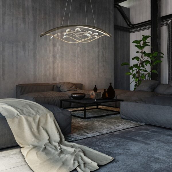 Modern living room featuring a minimalistic chandelier, grey sofas, a cozy throw blanket, a coffee table with decorative items, and a green plant, set against a textured concrete wall.
