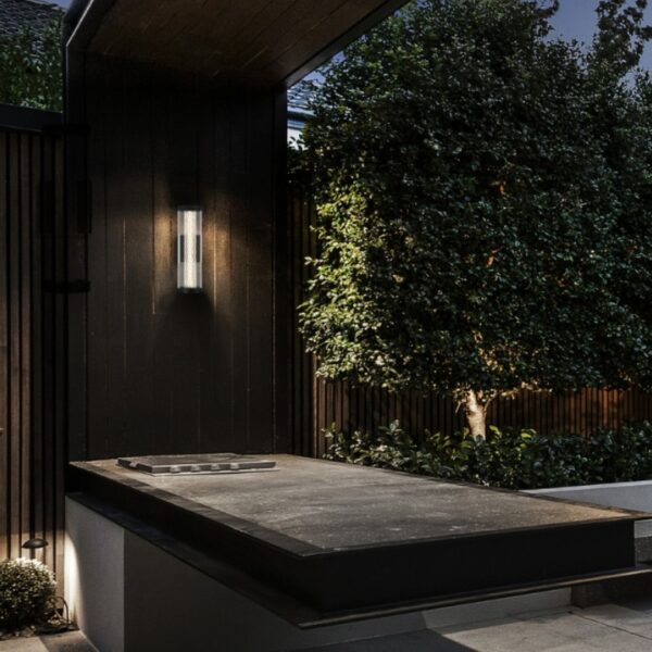 Modern outdoor space featuring a sleek vertical light fixture, a minimalist stone countertop, and lush greenery, ideal for evening gatherings and ambiance.
